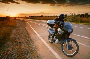 man sitting on motorcycle at sunset